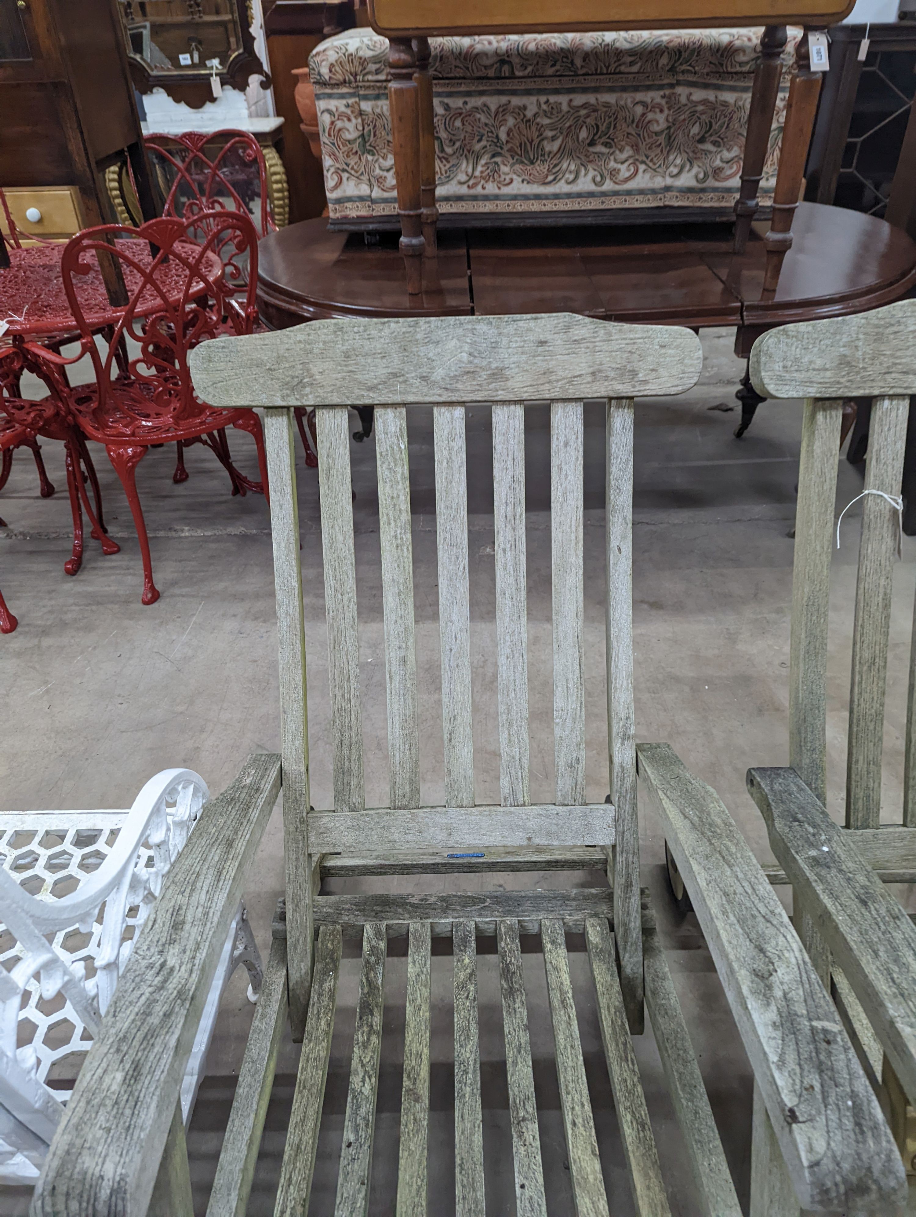 A pair of slatted weathered teak garden steamer chairs, width 59cm, height 97cm